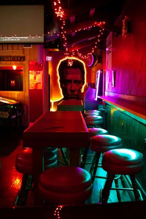 Vibrant neon-lit bar with artistic decor and empty seating, creating an inviting and modern atmosphere.