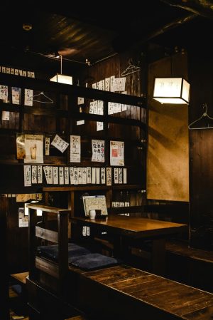 Warm interior of a traditional Japanese restaurant with wooden furniture and lantern lighting.